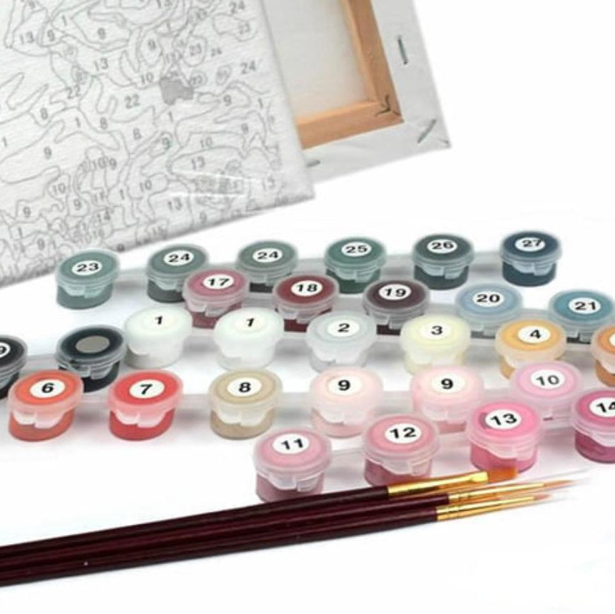 Set of paint pots with numbers and two brushes on a white background with a numbered stretch framed canvas