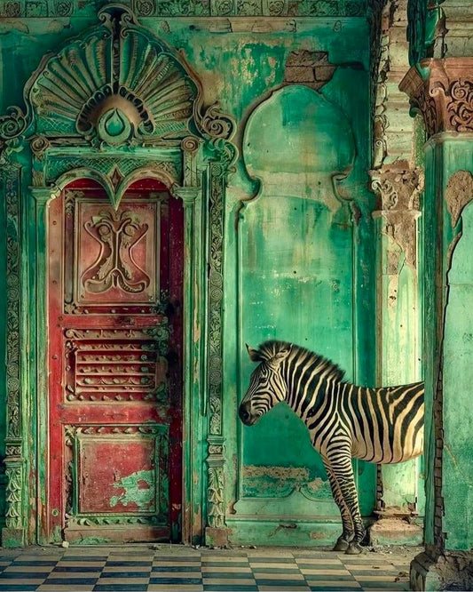 Zebra standing in front of an ornate, green door with a red frame.