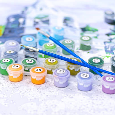 Close up of paint by number canvas, paint pots and brushes