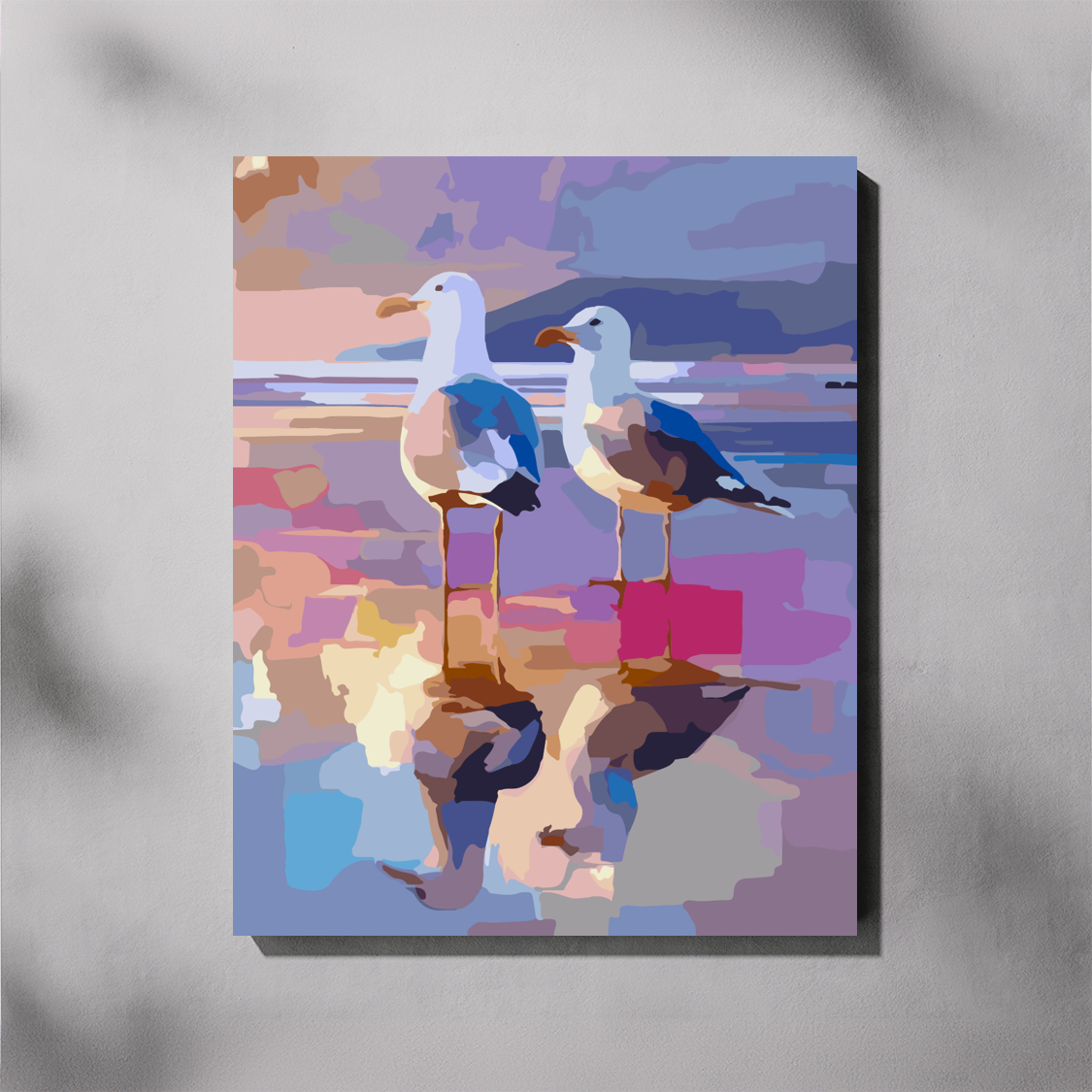 A completed paint by number canvas wall art print featuring an abstract, colorful depiction of two seagulls standing in shallow water with reflections, shown hanging on a light gray wall