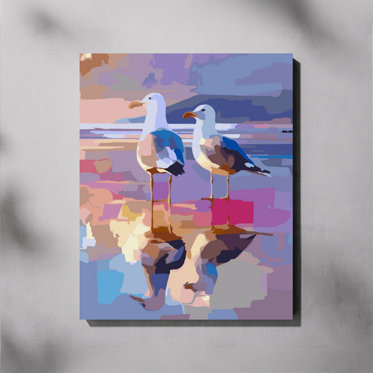 A completed paint by number canvas wall art print featuring an abstract, colorful depiction of two seagulls standing in shallow water with reflections, shown hanging on a light gray wall