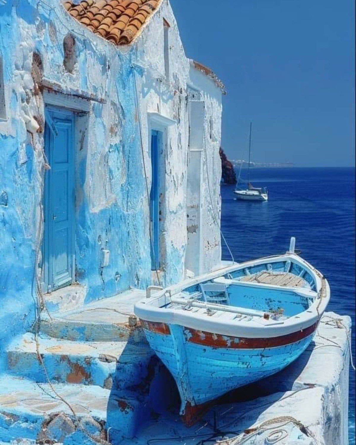 Blue building with a boat on a dock by the ocean