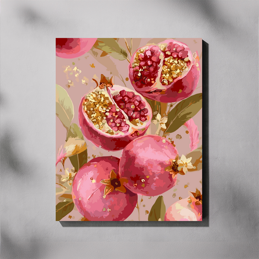 A vertical canvas paint by number featuring a stylized painting of pink pomegranates, some whole and some cut open to reveal red seeds and gold-toned highlights, set against a soft blush background with green leaves. The canvas is shown hanging on a light gray wall with soft shadow overlays.