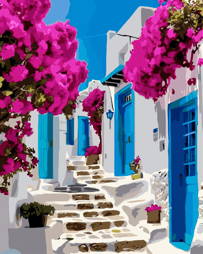 Colorful street scene with white buildings, blue doors, and pink flowers in a Mediterranean setting.