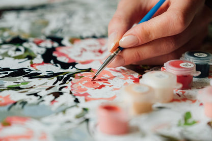 Hand painting a floral design on fabric with a brush