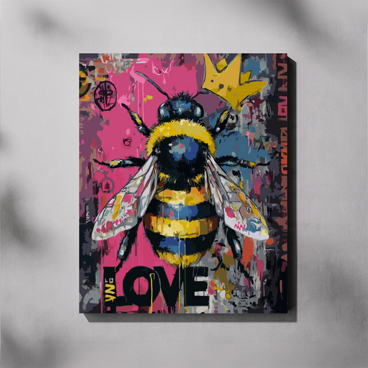 A square canvas wall art print featuring a stylized bumblebee over a colorful graffiti-style background with pink, blue, yellow, black, and white elements, shown hanging on a light gray wall.