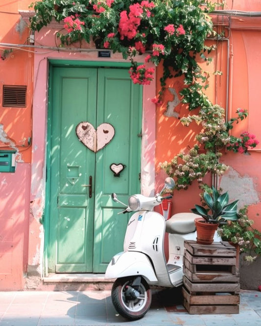 White scooter parked in front of a pink building with a green door and heart decorations.