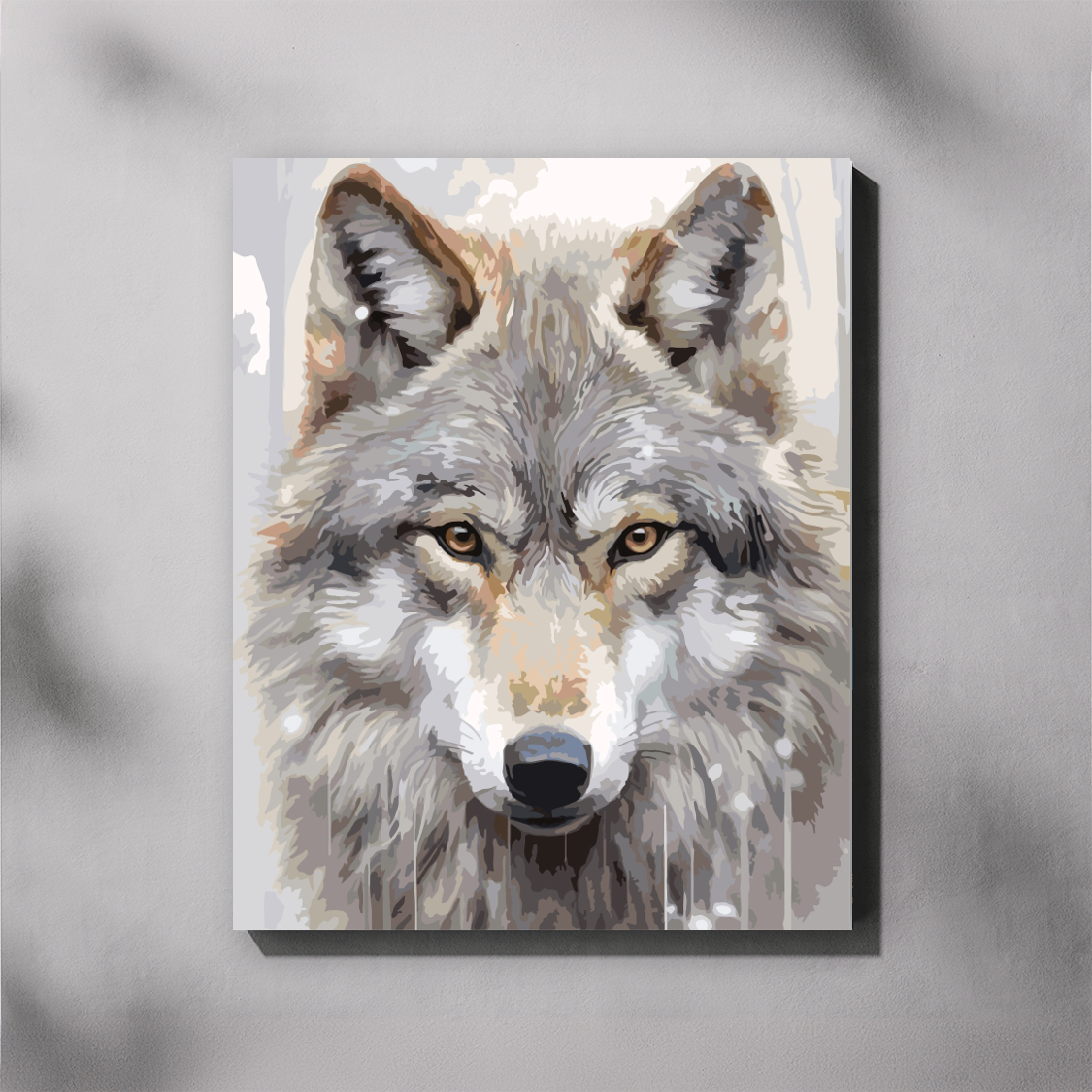 A paint by number canvas showing a close-up painted portrait of a gray wolf with amber eyes, displayed against a light gray wall with soft shadow overlays.