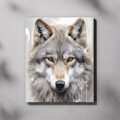 A paint by number canvas showing a close-up painted portrait of a gray wolf with amber eyes, displayed against a light gray wall with soft shadow overlays.