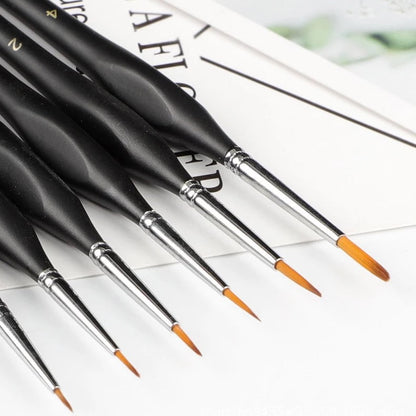 Set of black paintbrushes with orange tips on a white surface