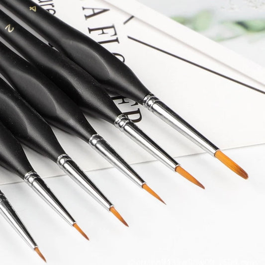 Set of black paintbrushes with orange tips on a white surface
