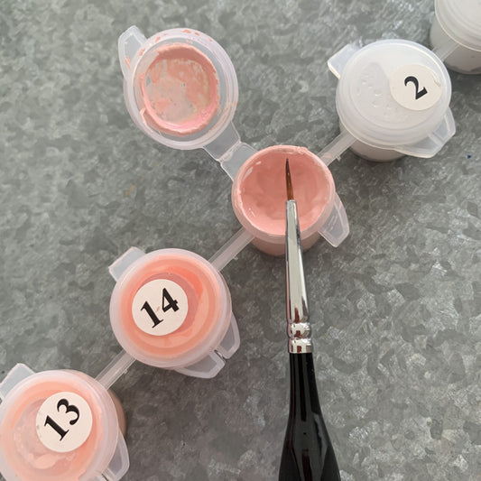 Set of pink paint containers with numbers and a brush on a gray surface