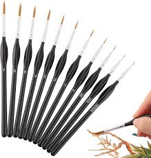 Set of small paintbrushes with a hand holding one, on a white background
