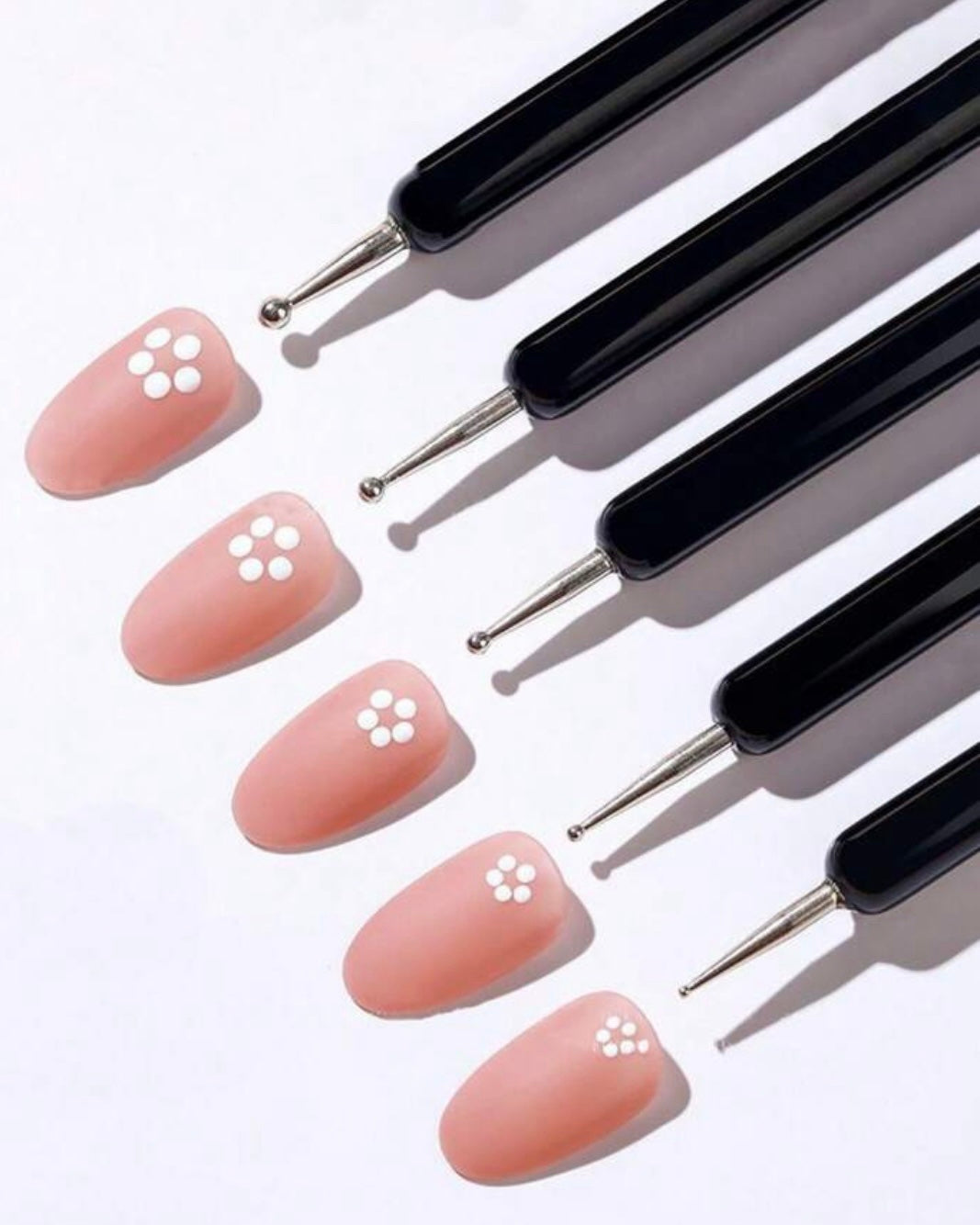 Set of art tools with black handles and pink nail samples on a white background