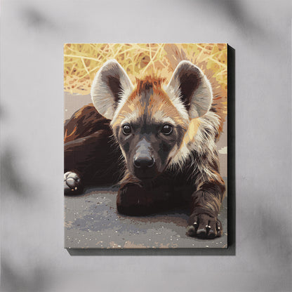 Hyena Cub paint by number kit — completed canvas mockup of a spotted hyena cub lying down and looking directly at the camera with soft green grass in the background
