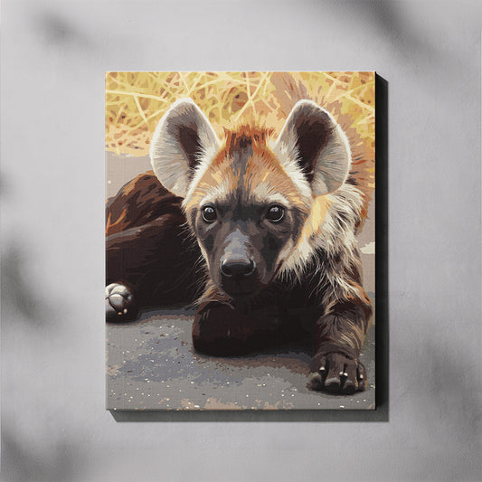 Hyena Cub paint by number kit — completed canvas mockup of a spotted hyena cub lying down and looking directly at the camera with soft green grass in the background
