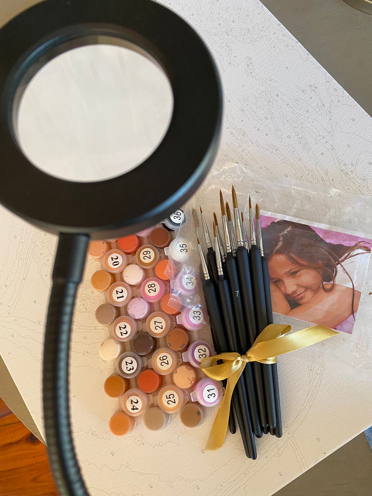 Set of paintbrushes and color swatches on a table with a magnifying glass.