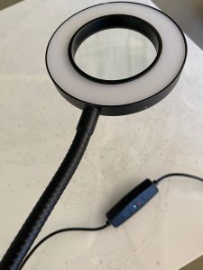Black magnifying glass with a white light on a white surface