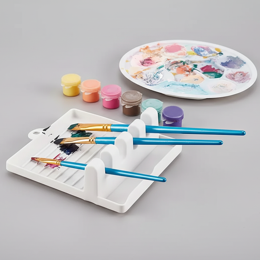 Paintbrush holder with paintbrushes, jars of paint, and a paint palette on a gray background